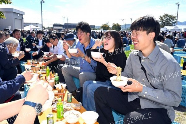並んで買い求めたそばを食べ笑顔の来場者（午前１０時２０分ごろ、塩原真撮影）