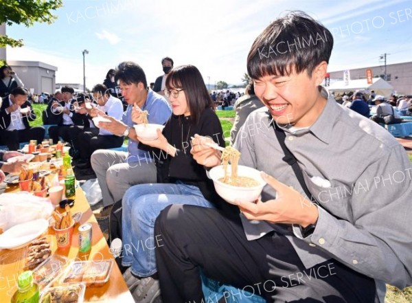 並んで買い求めたそばを食べ笑顔の来場者（午前１０時２０分ごろ、塩原真撮影）