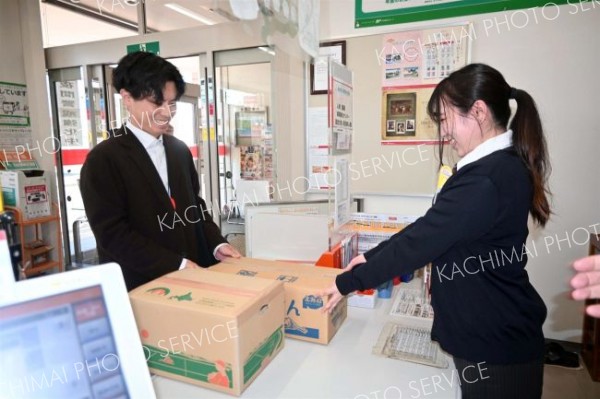 ぽすちょこ便を活用して届いた野菜を窓口で受け取る町民（左）