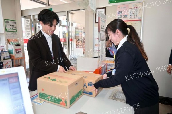 ぽすちょこ便を活用して届いた野菜を窓口で受け取る町民（左）