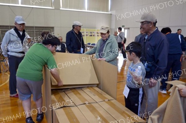 地域住民とダンボールベッドの組み立てに挑戦する児童たち