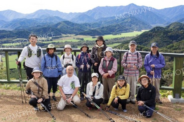 山頂展望台まで歩き、日高山脈の雄大な景色をバックに記念撮影する参加者ら