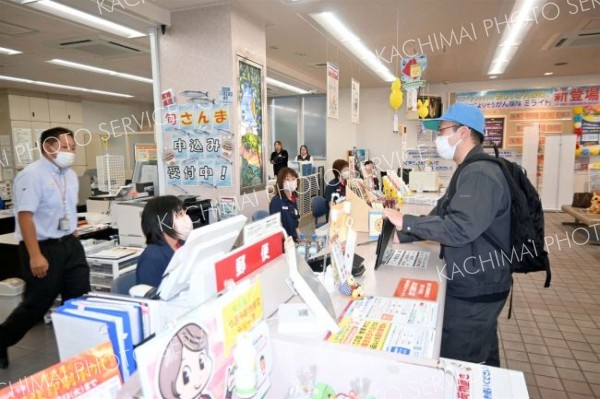 無言で現金を要求する犯人役の署員（右）に対応する局員たち