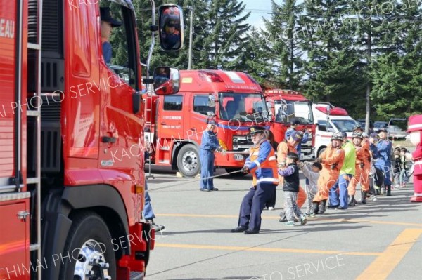 消防車と綱引きする参加者ら