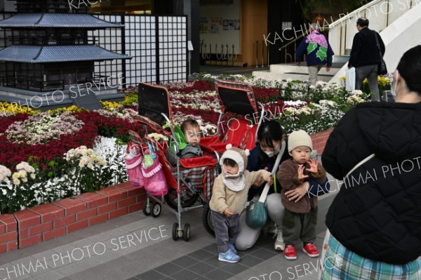 はい、ポーズ―。満開となった菊花の前で記念撮影をする「おびひろ菊まつり」の来場者（２９日、とかちプラザで。須貝拓也撮影）