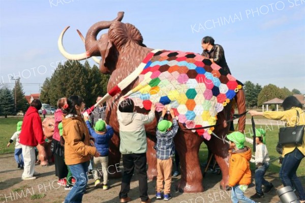 ナウマンゾウの親子模型にブランケットとマフラーを取り付ける園児ら