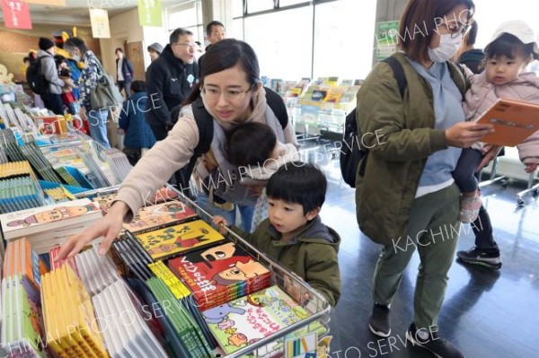 絵本を手に取る家族連れ（助川かおる通信員撮影）