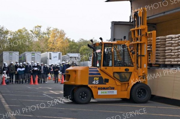 トラックから砂糖をフォークリフトで運び出す様子を見学する生徒たち