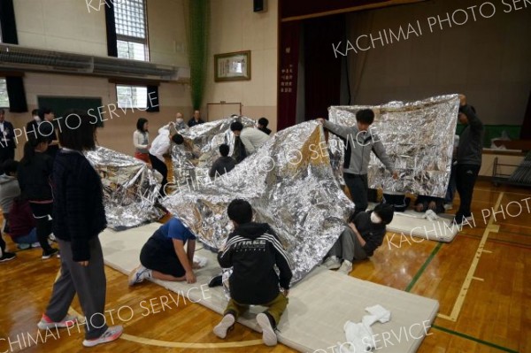 保温用アルミシートによる保温状態などを確認する子どもたち