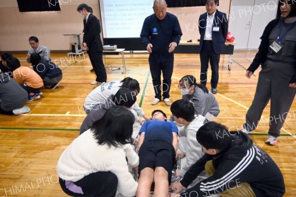 保温用アルミシートを用いた応急担架搬送を体験する子どもたち