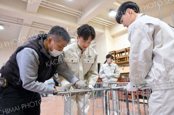 鉄筋を結束線でつなぐ作業を体験する生徒たち