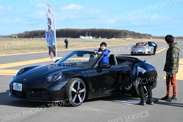 空まで飛んでいきそー。延伸した滑走路で行われたスポーツカーの体験試乗で記念撮影を行う親子（２２日、大樹町の北海道スペースポートで。須貝拓也撮影）