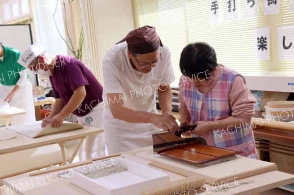 利用者にそば打ちを手ほどきする沼田代表