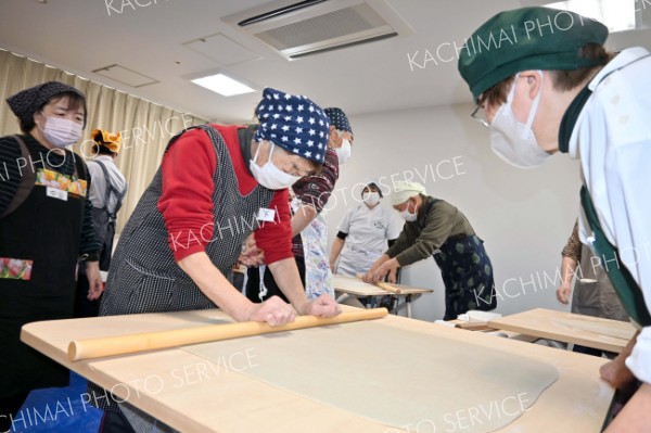 真剣な様子で麺棒を使って生地を均一に伸ばす参加者