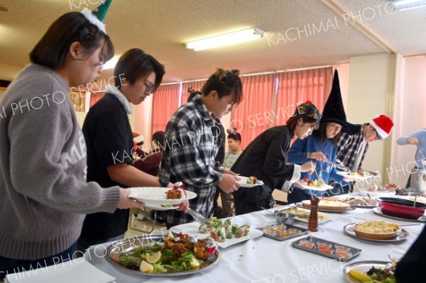クリスマスにちなんだ仮装もして、好みの料理を取り分ける学生たち