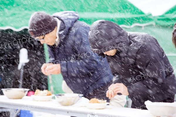 名物の「カニ早食い競争。雪や寒さに負けず、食べる速度を早める参加者ら。貴重な旬の味、本当はゆっくり味わって食べたいのだが…