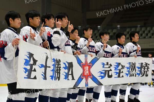 ３位決定戦で勝利し全国大会出場が決定。チームの横断幕を持ちカメラの前で胸を張る中学アイスホッケー全十勝Ａの３年生（７日、札幌市月寒体育館で。塩原真撮影）