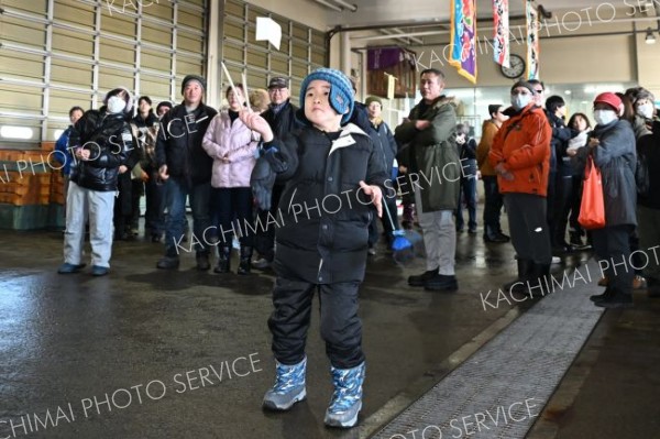 つかむぞ、１万円―。大津港大漁まつりで開かれた「ヒラヒラキャッチ」で１万円に模した紙を箸でつかもうと奮闘する子ども（７日、豊頃町大津漁協で。須貝拓也撮影）