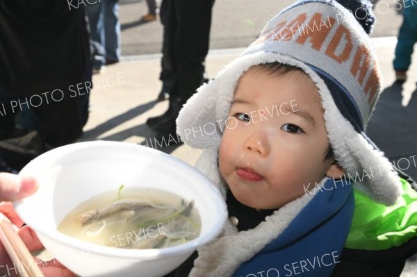 シシャモ、おいしい―。大津港大漁まつりで振る舞われた熱々のシシャモ鍋を味わい笑顔を浮かべる子ども（７日、豊頃町大津漁協で。須貝拓也撮影）