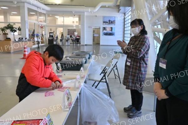 くじ運はボクに任せて！「とかち年末大売り出し」の抽選会でスクラッチカードを引き、カードをこする子ども（１３日、帯広市内の日産ドーム店で。金野和彦撮影）