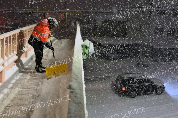 「午前１時までが山場だね」激しく雪が降る中で歩道橋を除雪する作業員（１４日、帯広市内で。塩原真撮影）