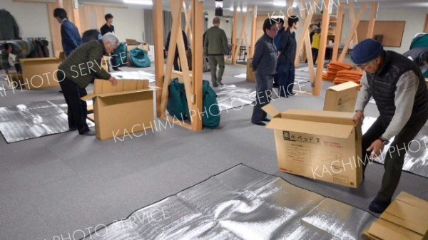 就寝前に自らの手で段ボールベッドを組み立てる参加者ら