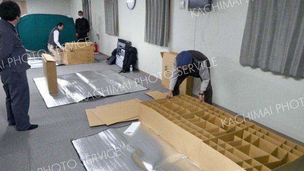 就寝前に自らの手で段ボールベッドを組み立てる参加者ら