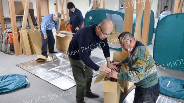起床後、町職員のアドバイスを受けながら、段ボールベッドなどを片付ける参加者ら