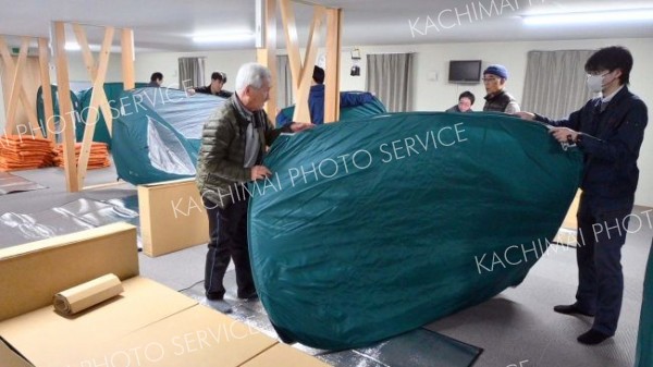 就寝前に自らの手でパーティションを設置する参加者ら