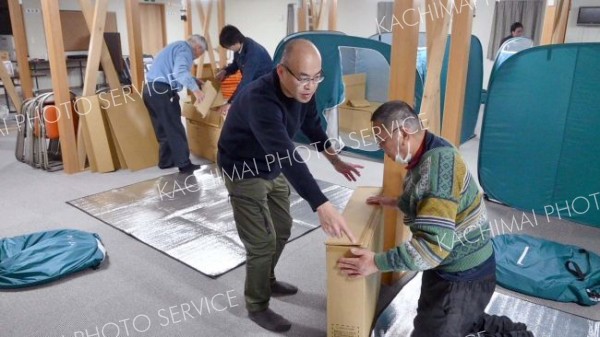 起床後、町職員のアドバイスを受けながら、段ボールベッドなどを片付ける参加者ら