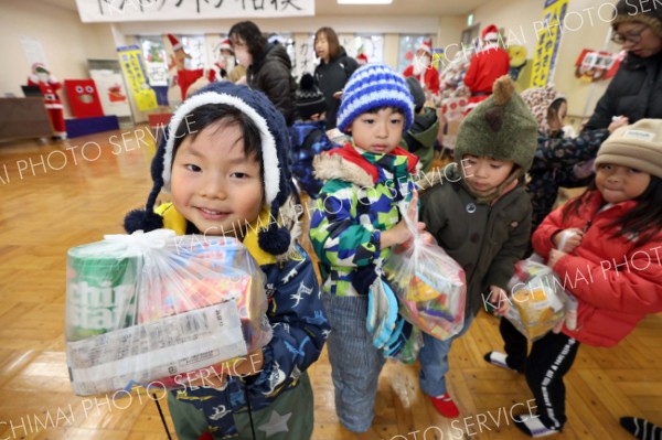 お菓子のプレゼントをもらい、うれしそうな子どもたち（２５日午前１０時２５分ごろ、助川かおる通信員撮影）