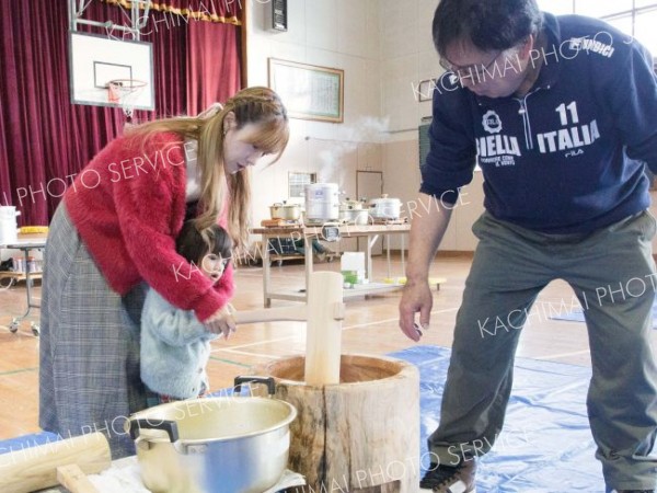 スタッフや保護者のサポートを受けながら餅をつく子ども