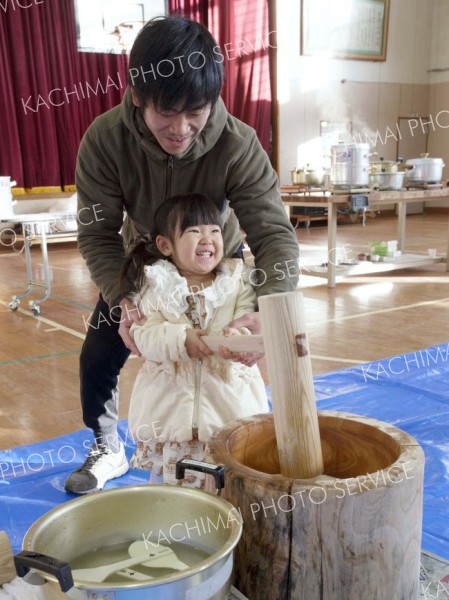 スタッフや保護者のサポートを受けながら、餅をつく子ども