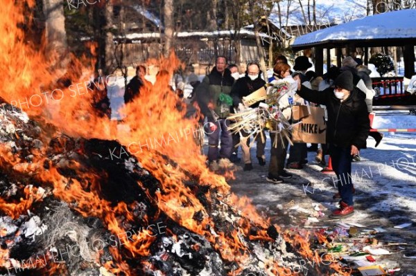 持ち寄った正月飾りなどを投げ入れる参拝者（１５日９時５０分ごろ、須貝拓也撮影）