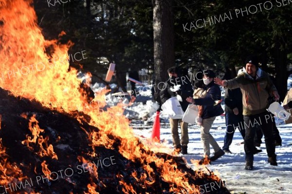 持ち寄った正月飾りなどを投げ入れる参拝者（１５日９時５０分ごろ、須貝拓也撮影）