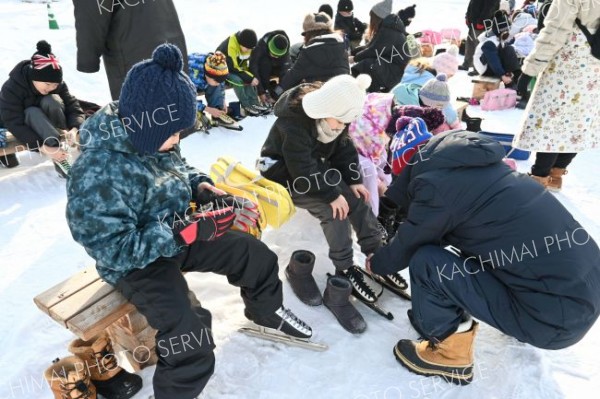 保護者らのサポートを受けながらスケート靴を履く児童