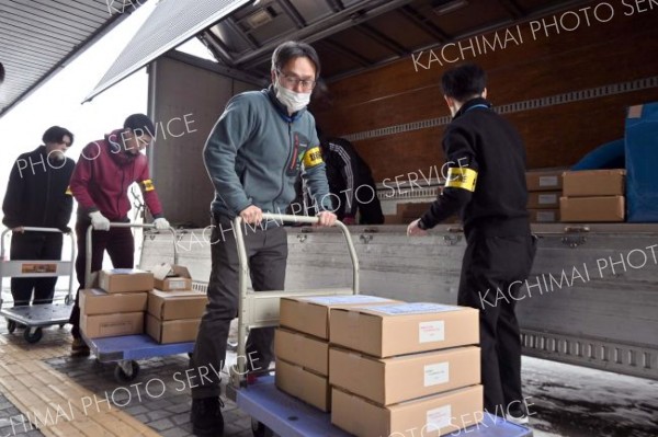 白い息を吐きながら投票用紙が入った段ボールを運び込む職員たち（２４日午前９時４０分ごろ）