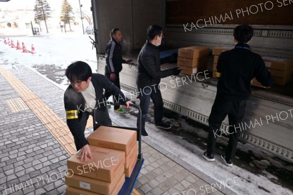 白い息を吐きながら投票用紙が入った段ボールを運び込む職員たち（２４日午前９時４０分ごろ）