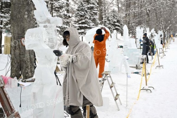 明日の開幕を前に、氷彫刻作品を完成を目指し、急ピッチで作業を進める参加者（２９日午前１１時ごろ。帯広市緑ヶ丘公園で。金野和彦撮影）