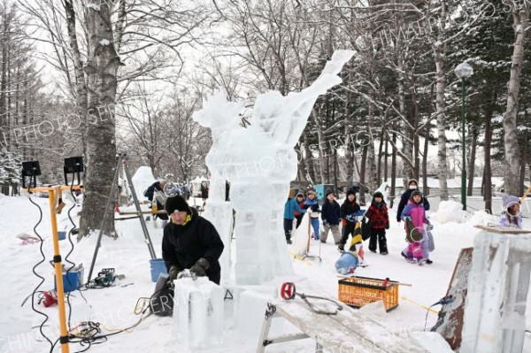 明日の開幕を前に、氷彫刻作品を完成を目指し、急ピッチで作業を進める参加者（２９日午前１１時ごろ。帯広市緑ヶ丘公園で。金野和彦撮影）