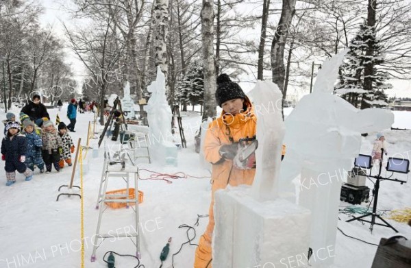 明日の開幕を前に、氷彫刻作品を完成を目指し、急ピッチで作業を進める参加者（２９日午前１０時５０分ごろ。帯広市緑ヶ丘公園で。金野和彦撮影）