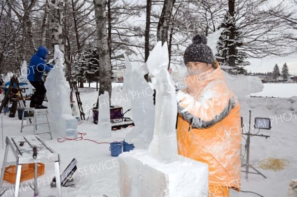 明日の開幕を前に、氷彫刻作品を完成を目指し、急ピッチで作業を進める参加者（２９日午前９時半ごろ。帯広市緑ヶ丘公園で。金野和彦撮影）
