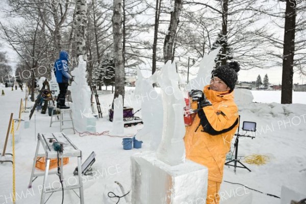 明日の開幕を前に、氷彫刻作品を完成を目指し、急ピッチで作業を進める参加者（２９日午前１０時２０分ごろ。帯広市緑ヶ丘公園で。金野和彦撮影）