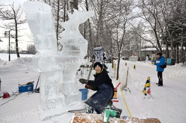 明日の開幕を前に、氷彫刻作品を完成を目指し、急ピッチで作業を進める参加者（２９日午前９時半ごろ。帯広市緑ヶ丘公園で。金野和彦撮影）