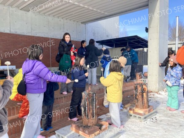 ウッドキャンドルであぶりながら焼きマシュマロを味わう参加者