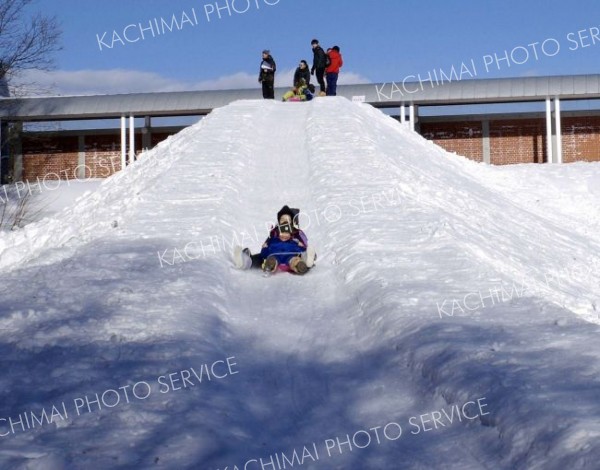 雪のジャンボ滑り台を楽しむ参加者