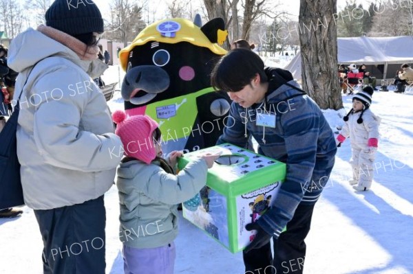 抽選会で、くじのポケットティッシュを引く参加者