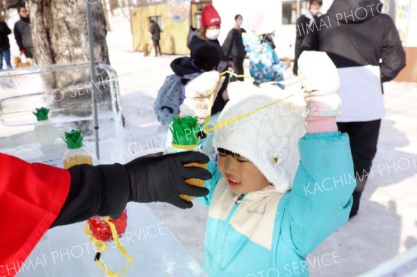 氷に囲まれた帯広ＹＥＧの「アイスＢＡＲ」で”光るボトル”を受け取る子ども（平栗玲香通信員撮影）