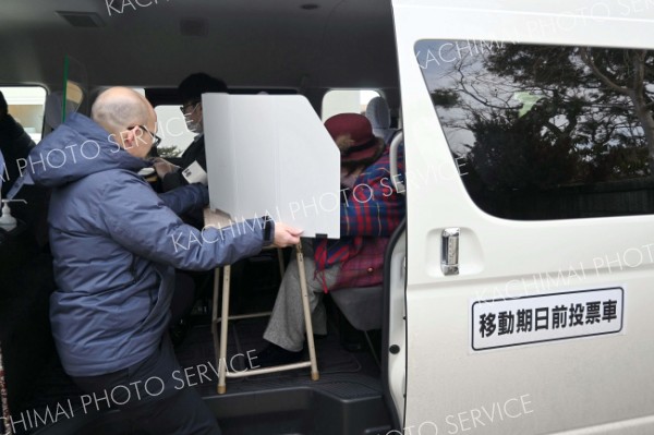 担当者らが見守る中、車の中で投票する坂本さん（右）＝３日、士幌町