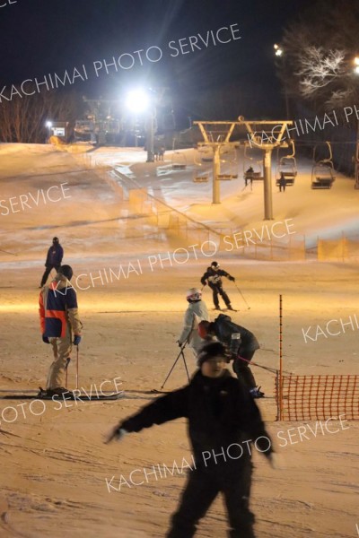 照明に照らされた幻想的なゲレンデを楽しむスキーヤー